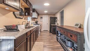 Une cuisine avec des meubles de rangement en bois, un plan de travail en granit, un four à micro-ondes, un réfrigérateur et un évier.
