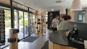 A reception area with a wooden reception desk, a computer, and a glass door leading outside.