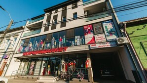 Edificio de dos plantas con un supermercado en la planta baja, con grandes ventanales y un cartel que anuncia una biblioteca.