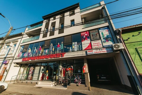 A two-story building with a supermarket on the ground floor, featuring large windows and a signboard advertising a library.
