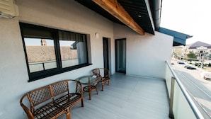 Un balcón con mobiliario de mimbre y vista a una calle y edificios.