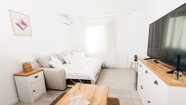 Un dormitorio moderno y minimalista con cama, mesita de noche y televisor.