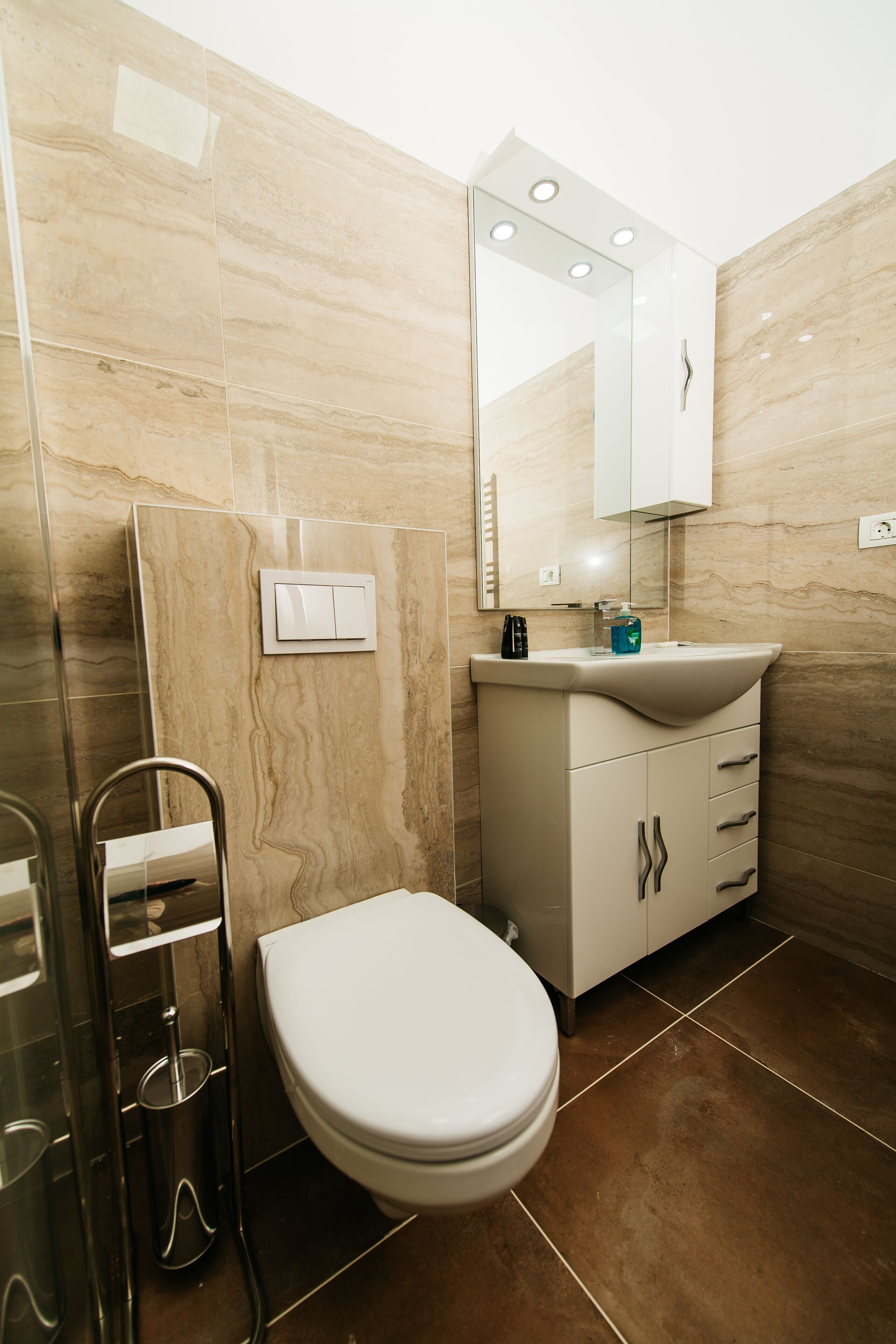 A modern bathroom with a white toilet, a sink with a mirror above it, and a shower area with a glass door.