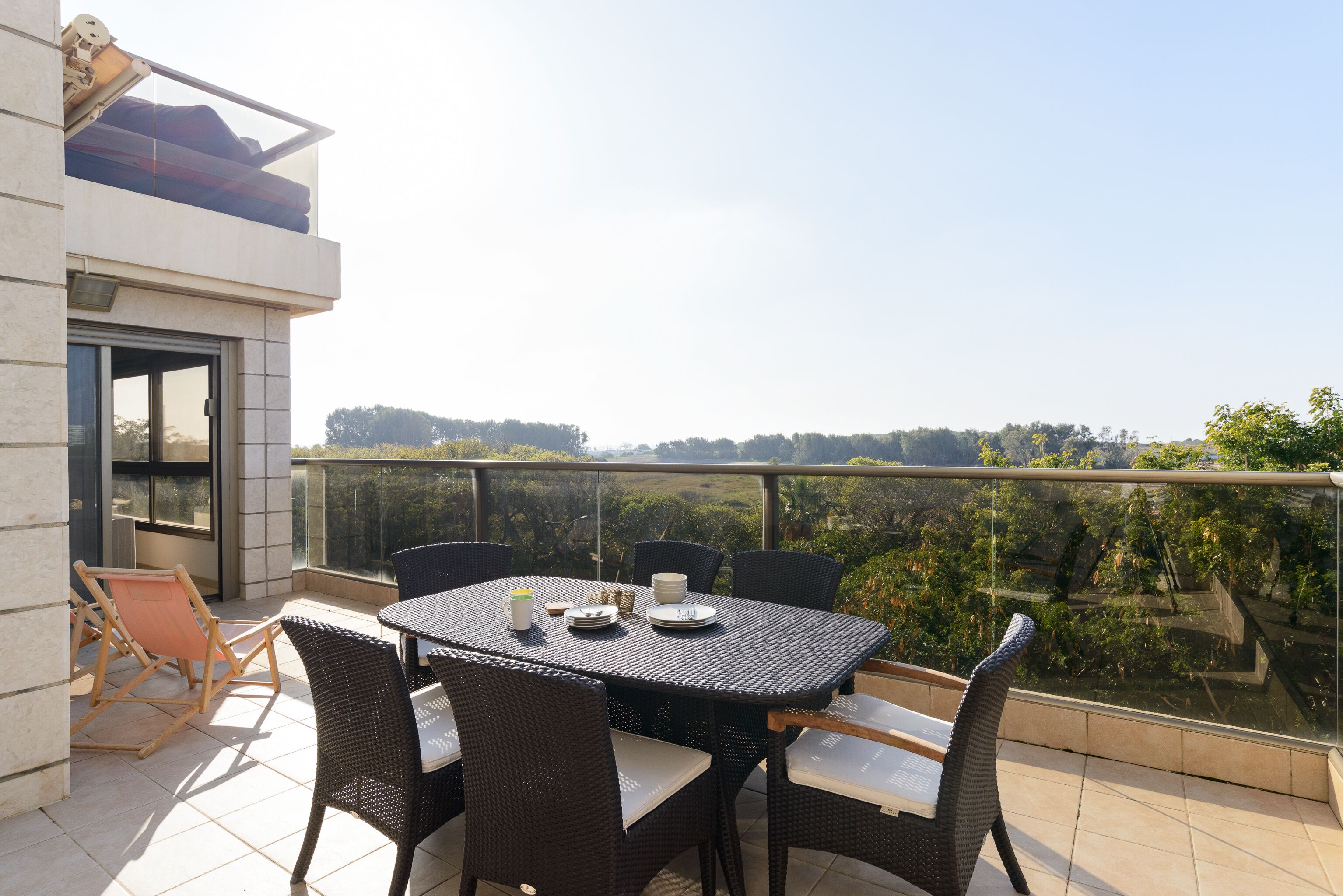 A balcony with a table and chairs, overlooking a scenic view.