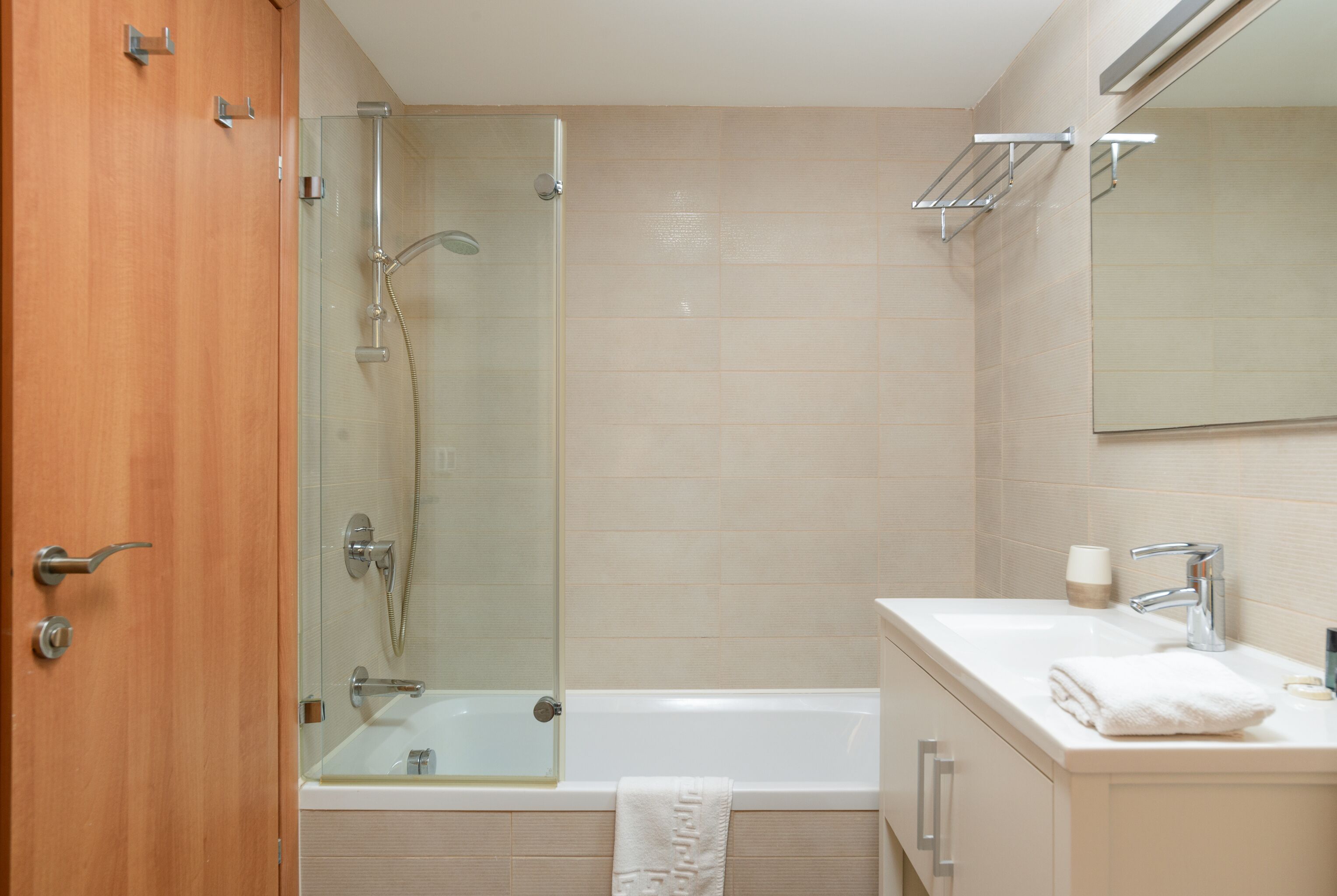 A modern bathroom with a glass-enclosed shower, a white bathtub, and a vanity with a mirror.