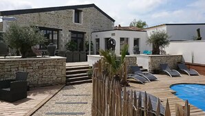 A stone building with a pool, outdoor seating, and a small structure with a clock. - Amazing villa in Nuaillé-d'Aunis with sauna (Nuaillé-d'Aunis)