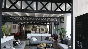A spacious living area with a high ceiling and exposed beams, furnished with grey sofas and a coffee table. - Amazing villa in Nuaillé-d'Aunis with sauna (Nuaillé-d'Aunis)