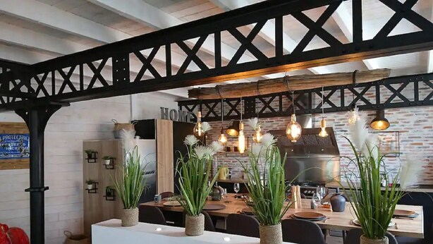 A modern kitchen with exposed brick walls, wooden beams, and hanging pendant lights. - Amazing villa in Nuaillé-d'Aunis with sauna (Nuaillé-d'Aunis)