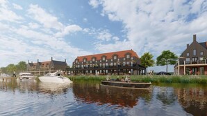 Un hotel a orillas del río, de estilo arquitectónico tradicional, con varios edificios de techos rojos y un muelle con barcos.