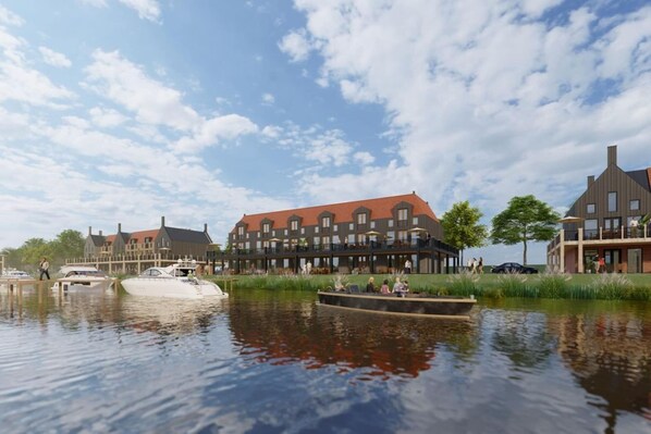 A riverside hotel with a traditional architectural style, featuring multiple buildings with red roofs and a dock with boats. - Loft Apartment by Veerse Meer Marina (Kamperland)