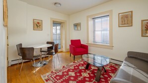 A modern living room with a dining area, a red armchair, a glass coffee table, and a grey sofa. - Contemporary Style with Old World Charm (Santa Fe)