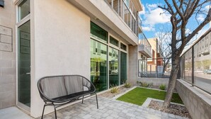 Ein modernes Gebäude mit Sitzbank, kleinem Rasen und Baum.