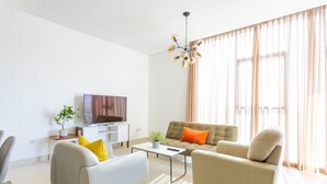 A modern living room with a sofa, armchairs, a coffee table, and a TV. - Nasma Luxury Stays - Pulse Residence  (Dubai)