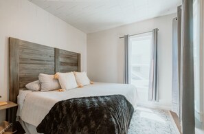 A bedroom with a large bed, a headboard, a nightstand, and a window with curtains. - A beautiful home near OSU campus (Corvallis)