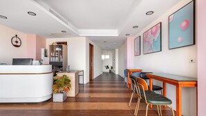 A hotel reception area with a curved reception desk, a seating area with chairs, a potted plant, and artwork on the walls. - Jhai-Wu (Hengchun)