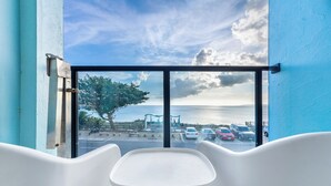 A balcony with a table and chairs, overlooking a parking area and a body of water. - Jhai-Wu (Hengchun)