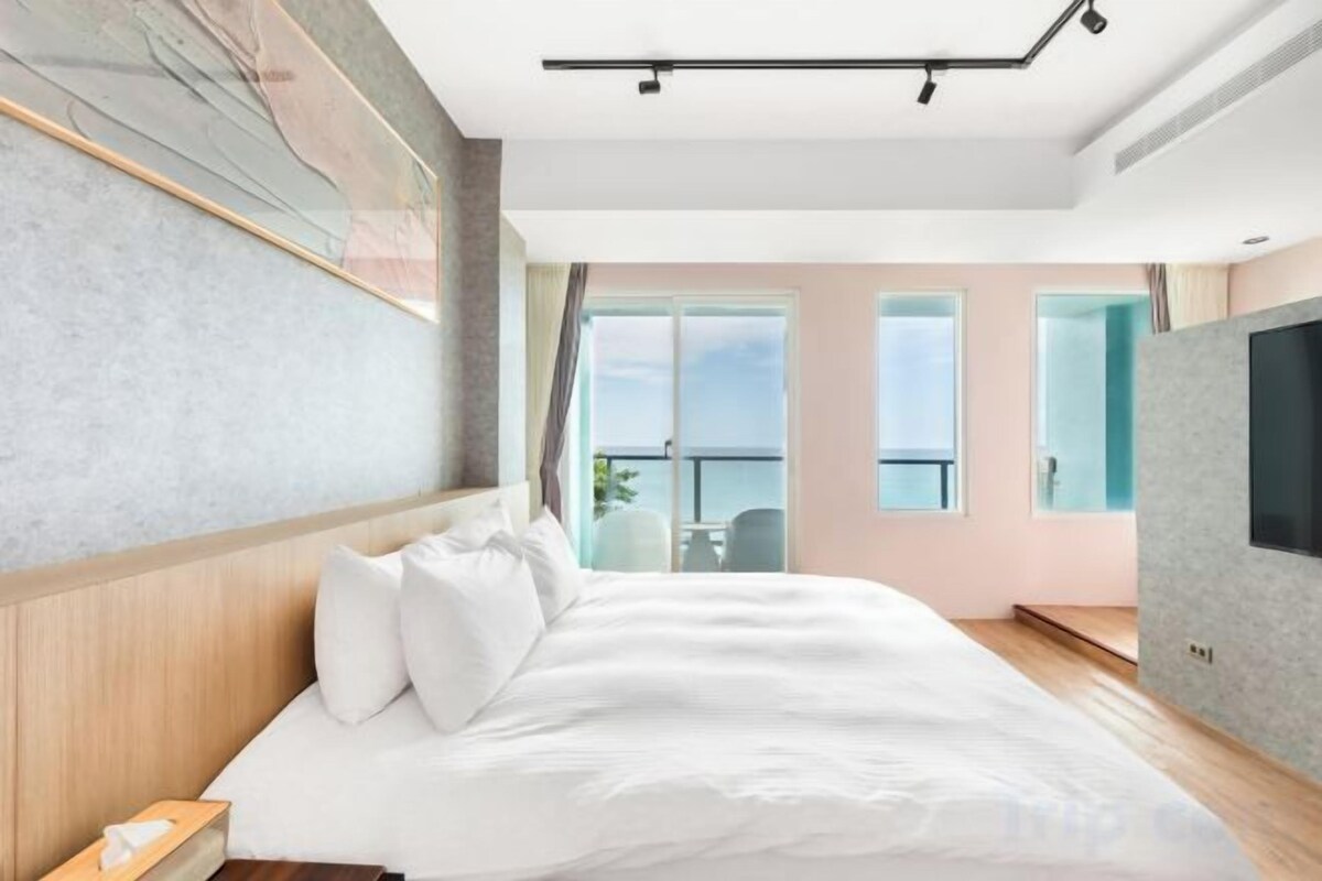 A hotel room with a bed, a TV, a window, and a balcony.