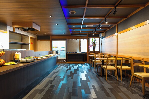 A modern restaurant interior with a long counter, wooden chairs, and a patterned floor.