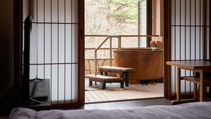 Een traditionele Japanse kamer met tatami vloeren, een houten tafel, een bank van tatami matten en een groot houten vat.