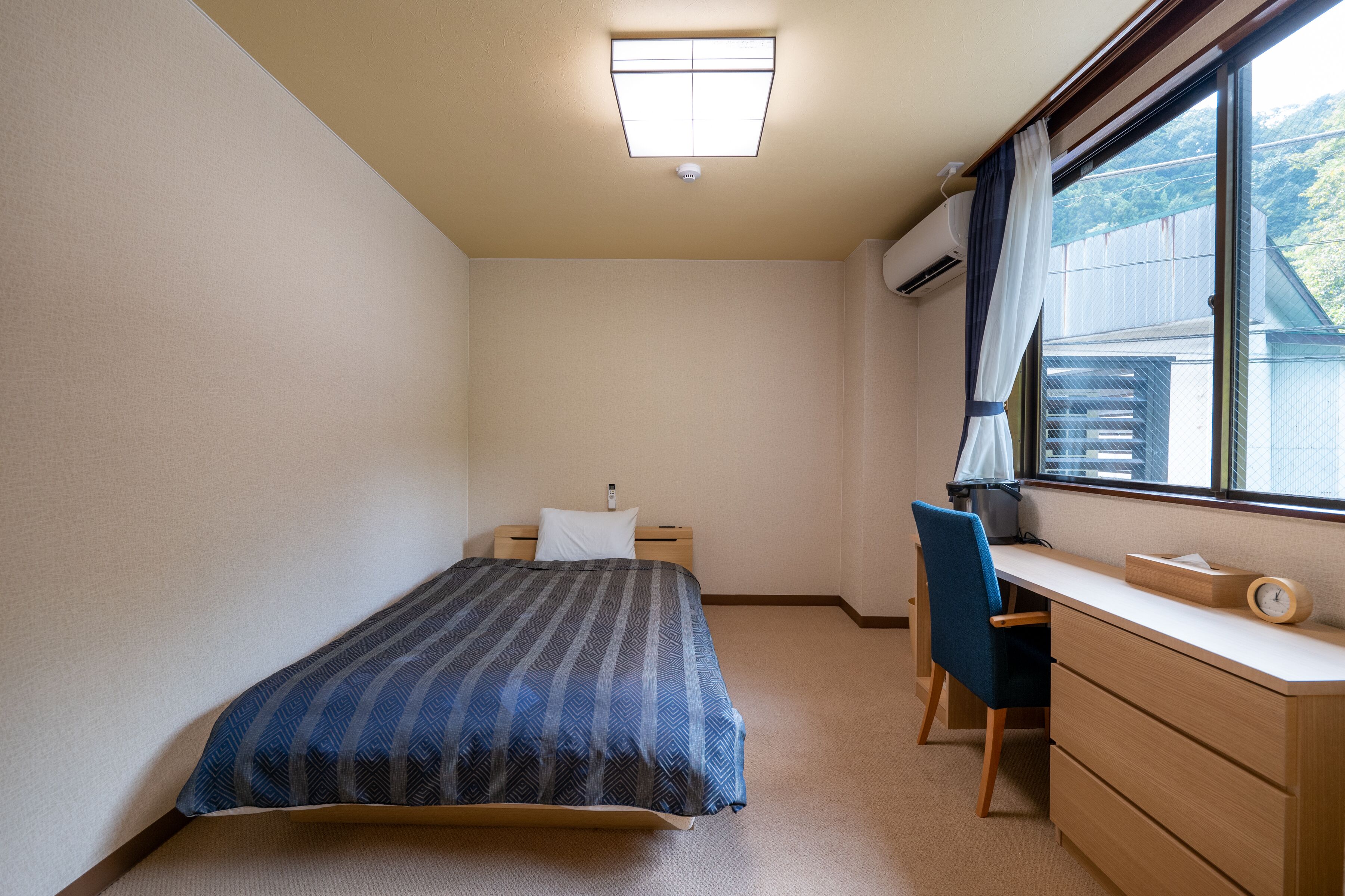 Un dormitorio con cama, escritorio y ventana con cortinas.