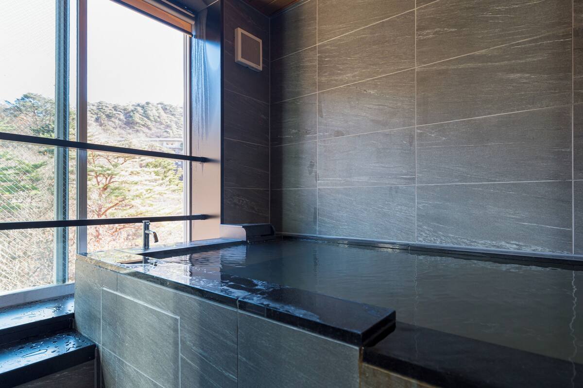 Un baño moderno con un ventanal grande, un lavabo empotrado y zona de ducha.