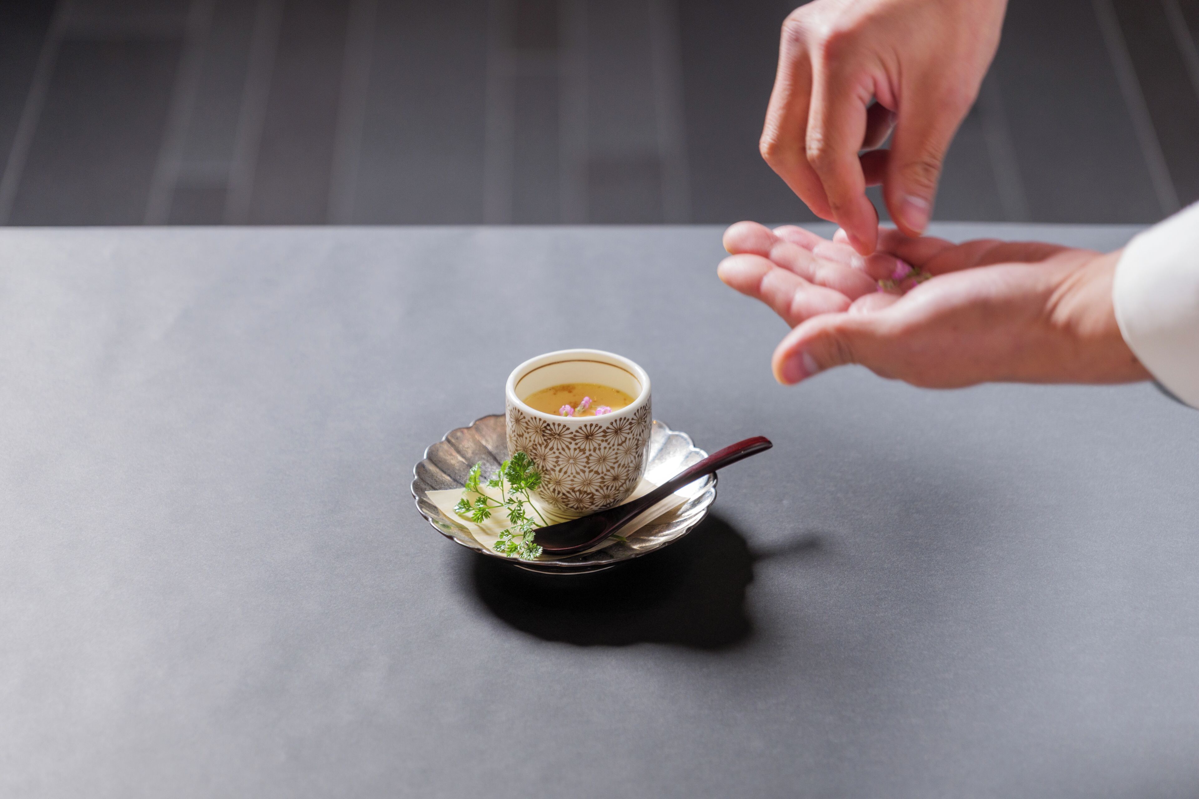 A cup of tea on a saucer with a spoon, placed on a table.