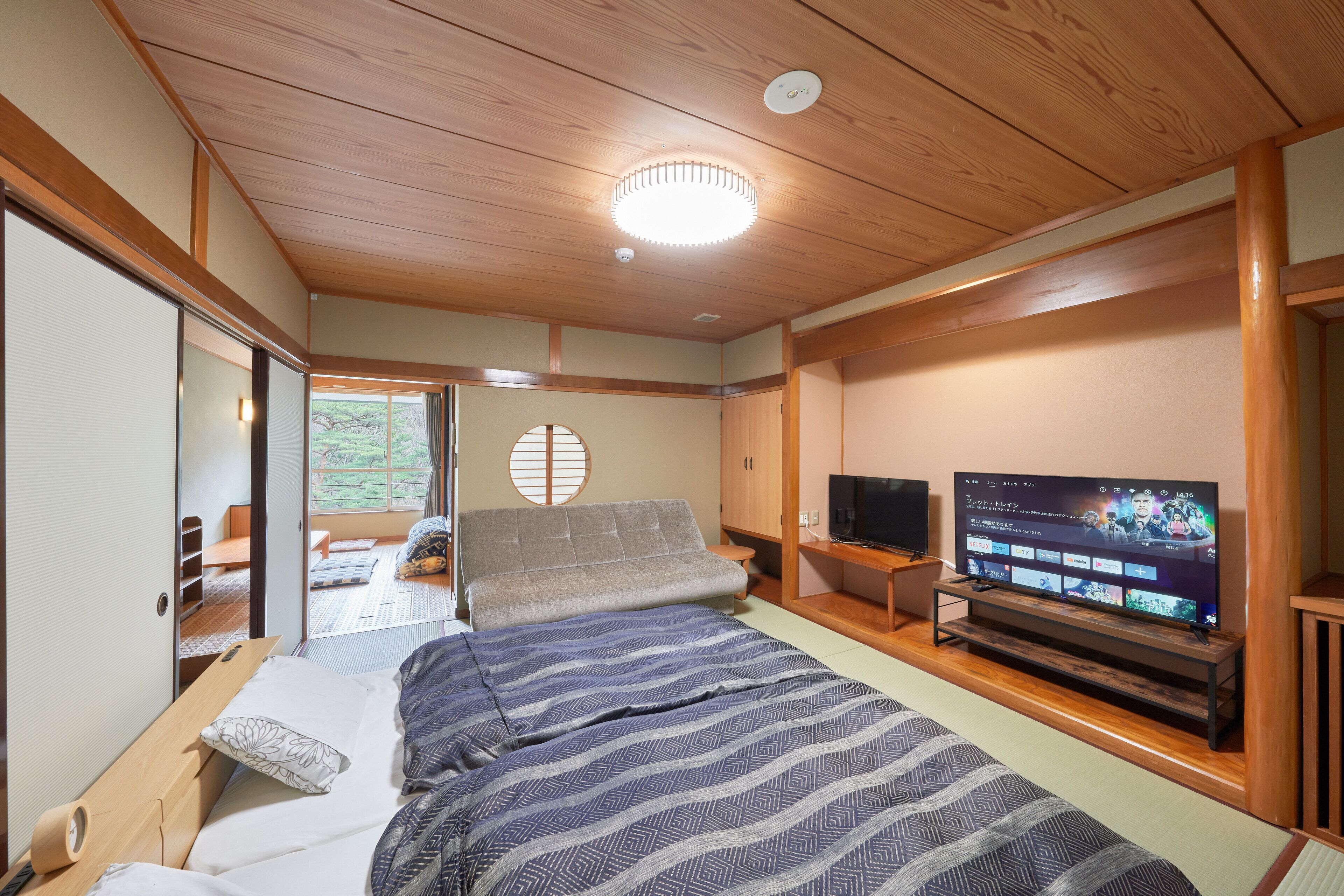A room with a bed, a television, and a sliding door leading to a balcony.