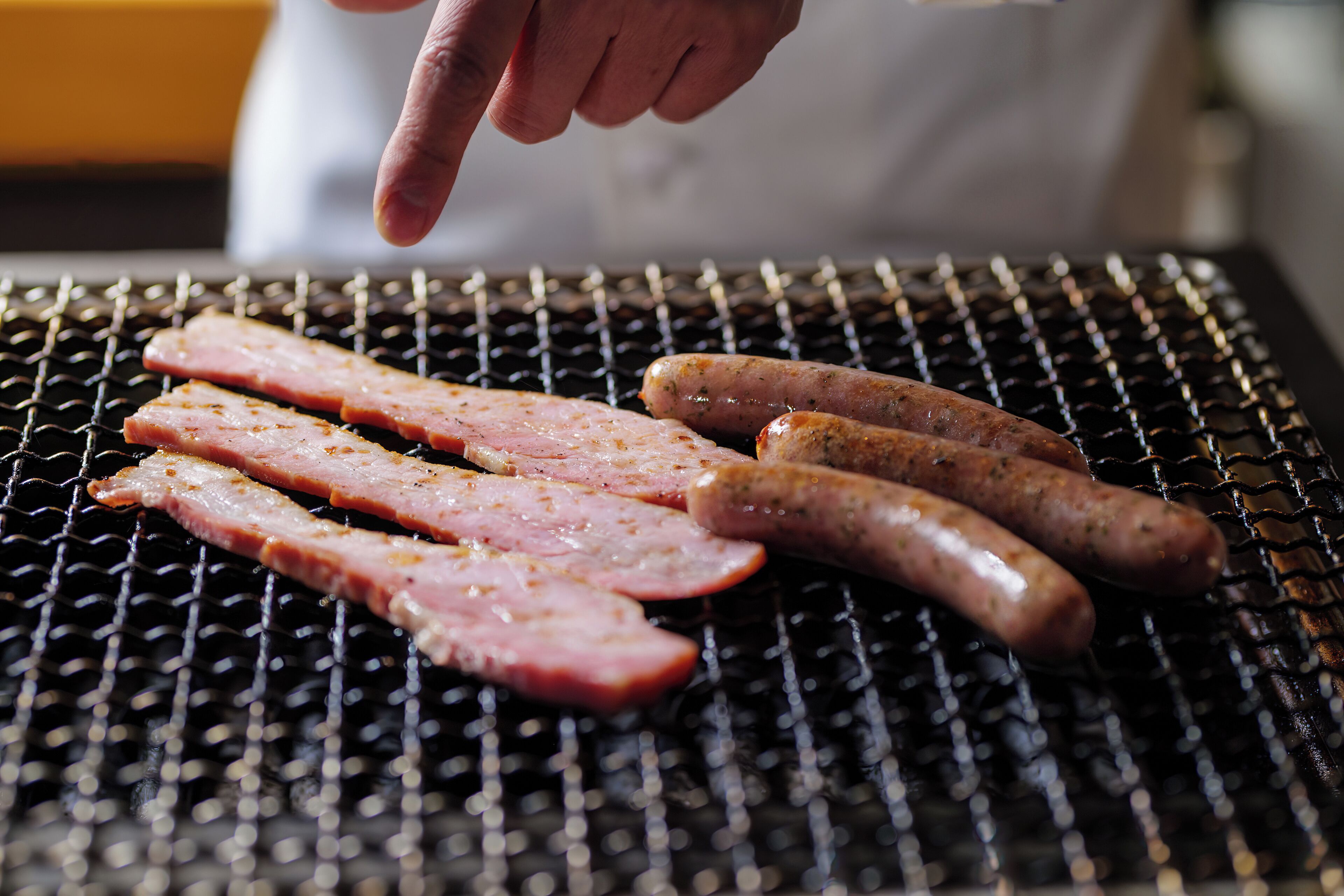 Des saucisses sont en train de griller sur une grille métallique.