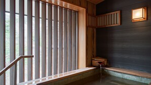 A traditional Japanese onsen with wooden sliding doors, a stone bench, and a small wooden table. - Nikko Garden Hotel (Nasushiobara)