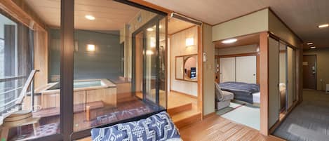 Ein traditioneller japanischer Raum mit Tatami-Böden, einer Schiebetür und Blick auf ein Thermalbadgebiet.