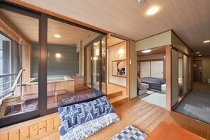 Een traditionele Japanse kamer met tatami vloeren, een schuifdeur en uitzicht op een bronnenlandschap.
