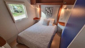 Une chambre à coucher de taille réduite, comprenant un lit, une fenêtre et une œuvre d’art accrochée au mur.