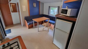 Une petite cuisine équipée d’un four à micro-ondes, d’une cuisinière et d’un petit réfrigérateur. Un coin salon avec un banc et une table est également à disposition.