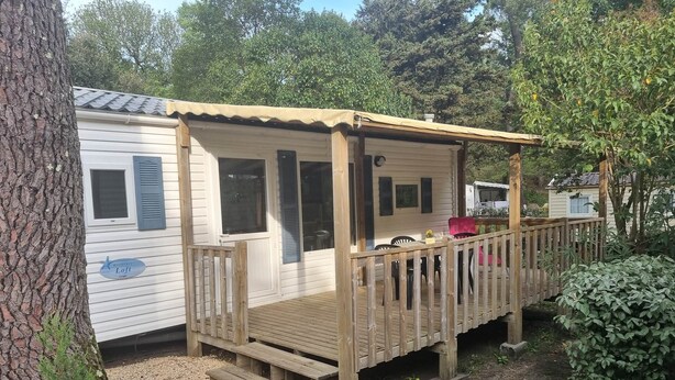 Une petite maison mobile d’un seul étage, dotée d’une terrasse en bois et d’un porche couvert.