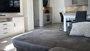Un soggiorno moderno con un divano grigio, una TV a schermo piatto e un'area pranzo con tavolo e sedie.