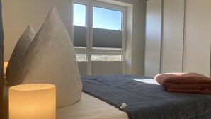 Una camera da letto con un letto, cuscini, una coperta, una lampada e una finestra.