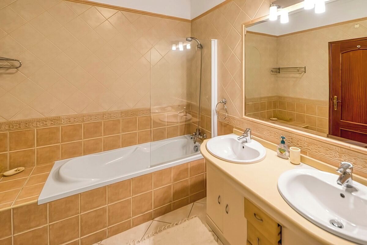 Ein Badezimmer mit einer Badewanne, zwei Waschbecken und einem großen Spiegel.
