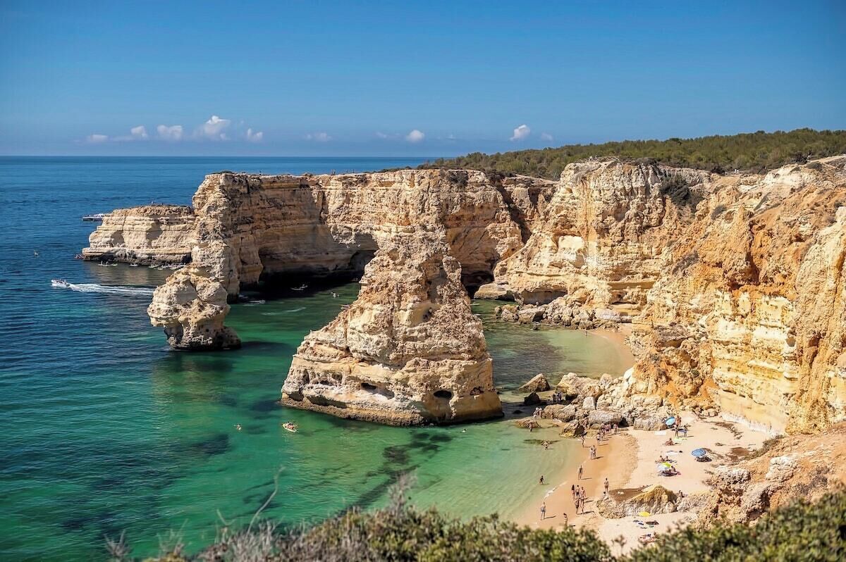 Un paisaje costero con acantilados, aguas turquesas cristalinas y una playa de arena.