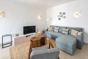 A living room with a TV, sofa, coffee table, and decorative wall lights. - Casa Yaneliz - renovated apartment on nice resort! (Carvoeiro)