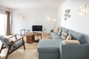 Olohuone, jossa on sohva, televisio ja sohvapöytä.