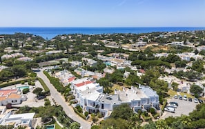 Eine Luftaufnahme einer Küstenwohngegend mit Häusern, einem markanten weißen Gebäude mit rotem Dach und freiem Blick auf das Meer.