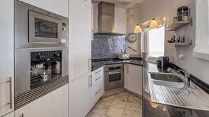 A modern kitchen with stainless steel appliances, a tiled backsplash, and a window providing natural light. - Casa Ocean View - 180 degrees sea view (Carvoeiro)