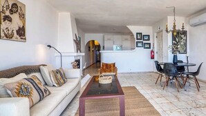 A living room with a sofa, a coffee table, and a dining area with chairs and a table. - Casa Ocean View - 180 degrees sea view (Carvoeiro)