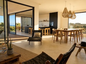 A modern interior with a dining area, kitchen, and a view of the outdoors.