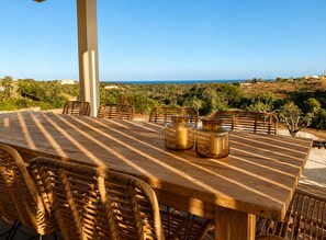 An outdoor dining area with a table and chairs, overlooking a coastal landscape. - Casa Mú | Luxury Villa & Private Pool (Lagoa)