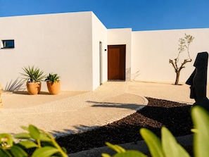 A modern building with a white exterior, a wooden door, and two potted plants. - Casa Mú | Luxury Villa & Private Pool (Lagoa)