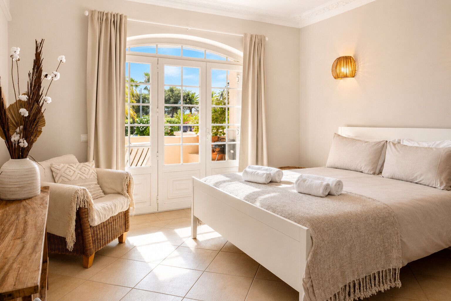Une chambre à coucher avec un lit, une chaise, une table et une fenêtre avec des rideaux.
