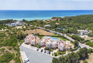 Vista aérea de una zona residencial costera con piscina, varios edificios y un estacionamiento.