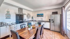A modern kitchen with a wooden dining table, black chairs, and a stainless steel refrigerator.