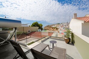 A rooftop terrace with a view of a coastal town, a large metal tank, and a potted plant. - The Beach House Carvoeiro - Cliffside Apartment (Carvoeiro)